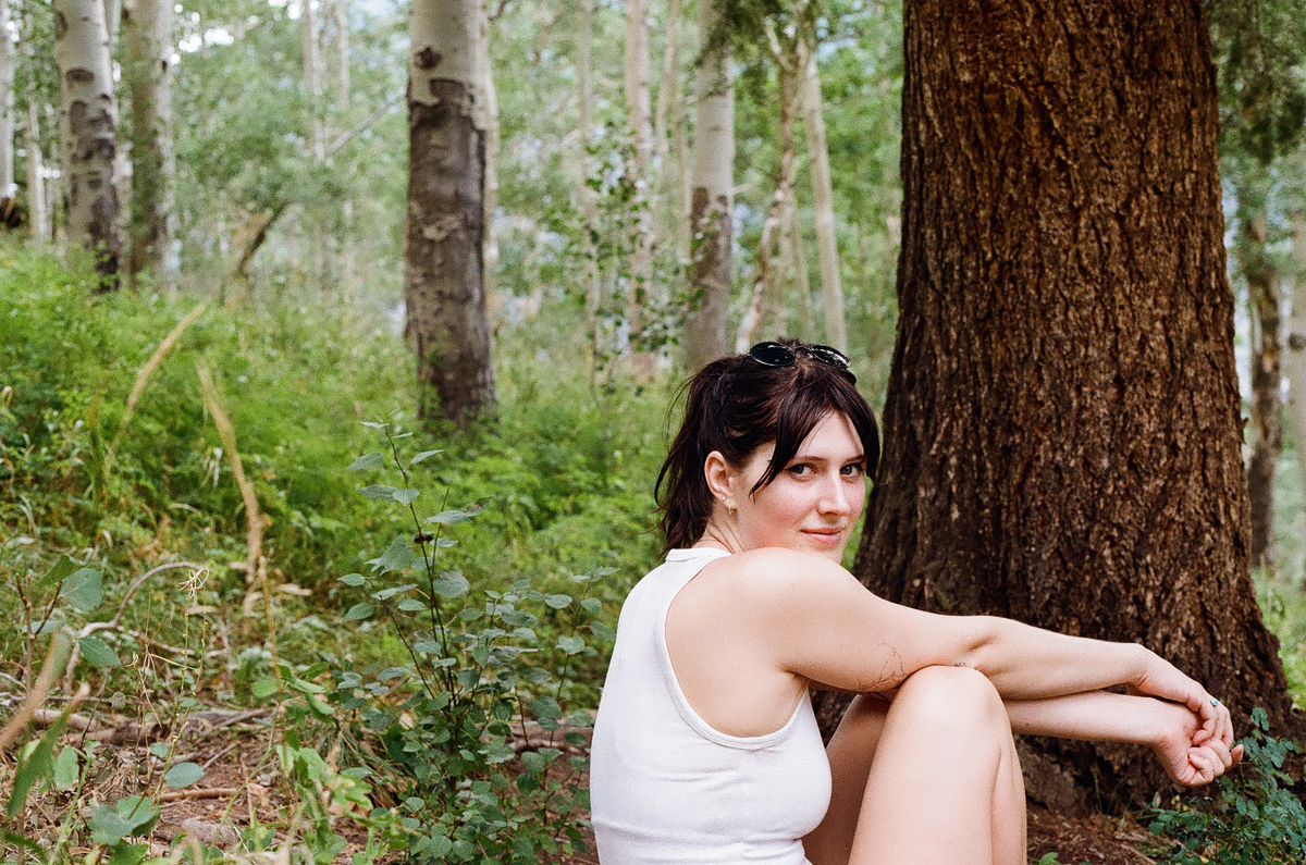 Portrait of artist Grace Kennison sitting in a Colorado forest.
