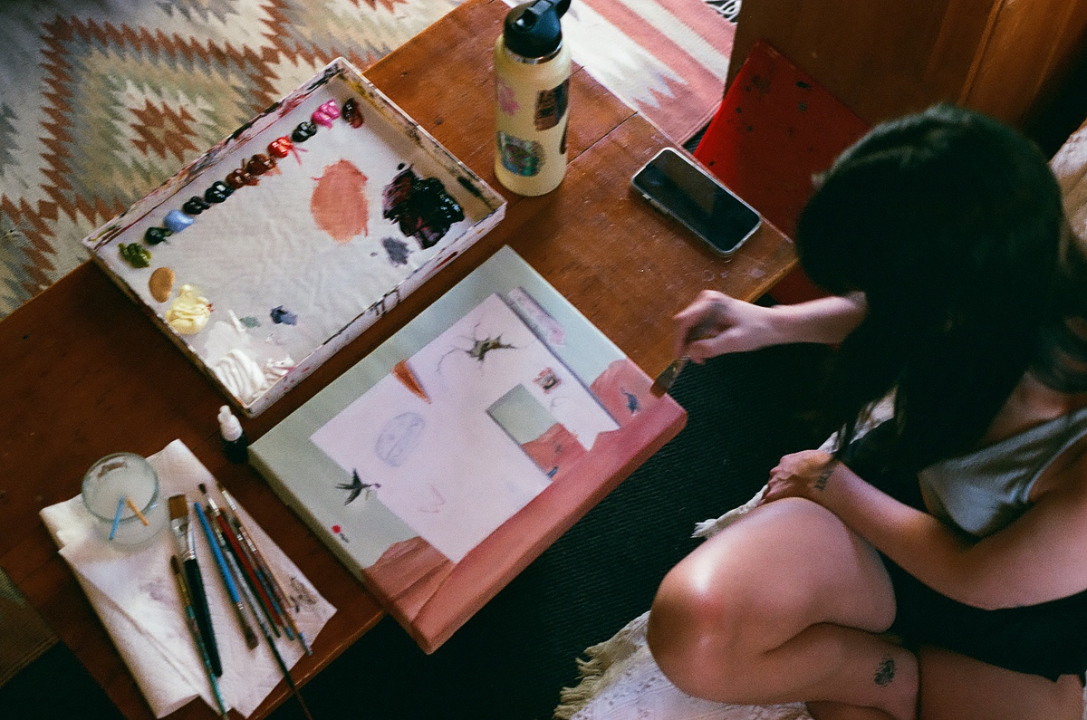 Ridgway, Colorado, artist Grace Kennison paints a small canvas on a wooden table.