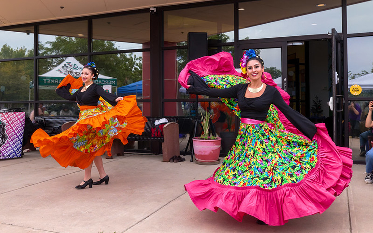 Two women dance in colorful dresses.