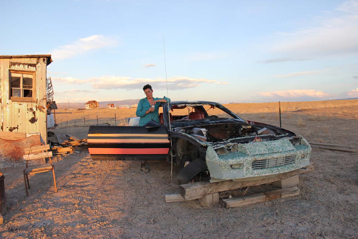Muza in the zone with the shed and the empty stock tank next to an old sports car.