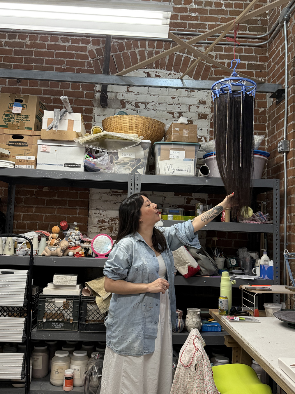 Artist Jennifer Ling Datchuk reaches up to touch a suspended sculptural work in her Phoenix studio.