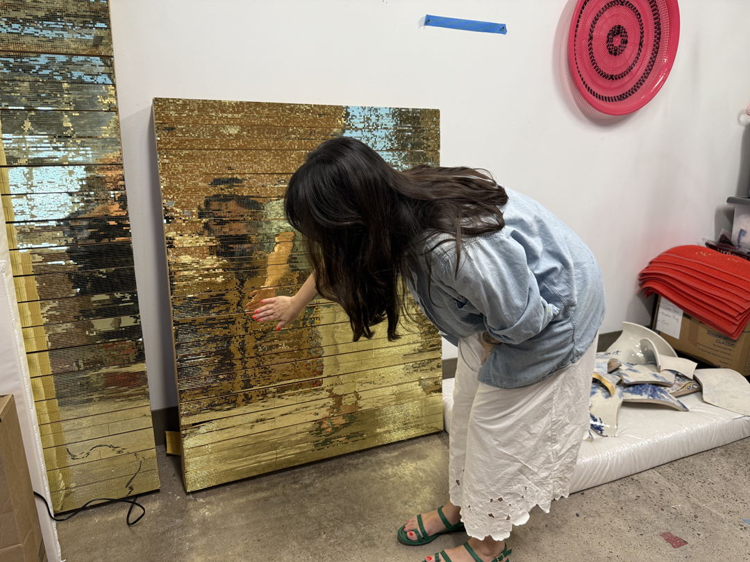 Jennifer Ling Datchuk examines a panel covered in golden mirrored tiles in her Phoenix studio.