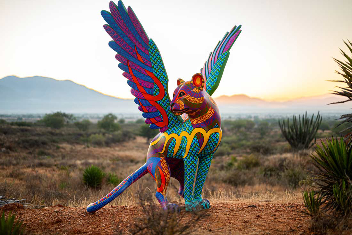 Winged lion referencing the Oaxacan alebrije tradition in a sweeping desertscape. Southwest Botanical Gardens have transformed into living contemporary art museums.