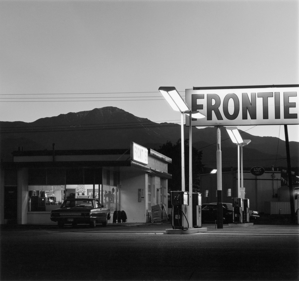 Black and white photo by Robert Adams showing a truck stop with Colorado's Pikes Peak in the background.