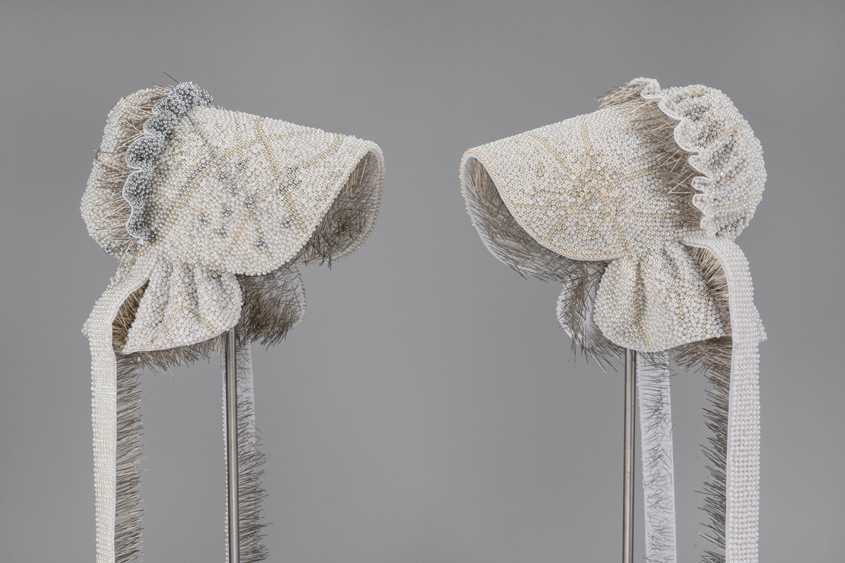 Two bonnets made of thousands of pearl-tipped corsage pins made by Utah-based artist Angela Ellsworth.