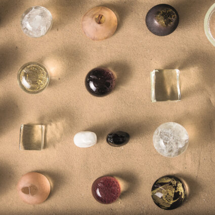 Glass sculptures nestled in sand by Judy Tuwaletstiwa, part of Abstracting Nature at Albuquerque Museum.