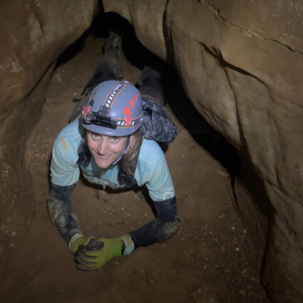 Artist Erika Jaeggli peers out from deep inside a cave.