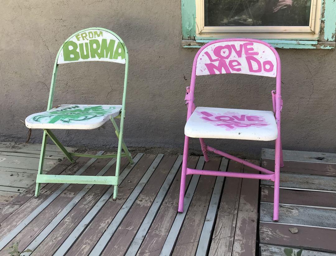 Painted lawn chairs in green and pink that read 