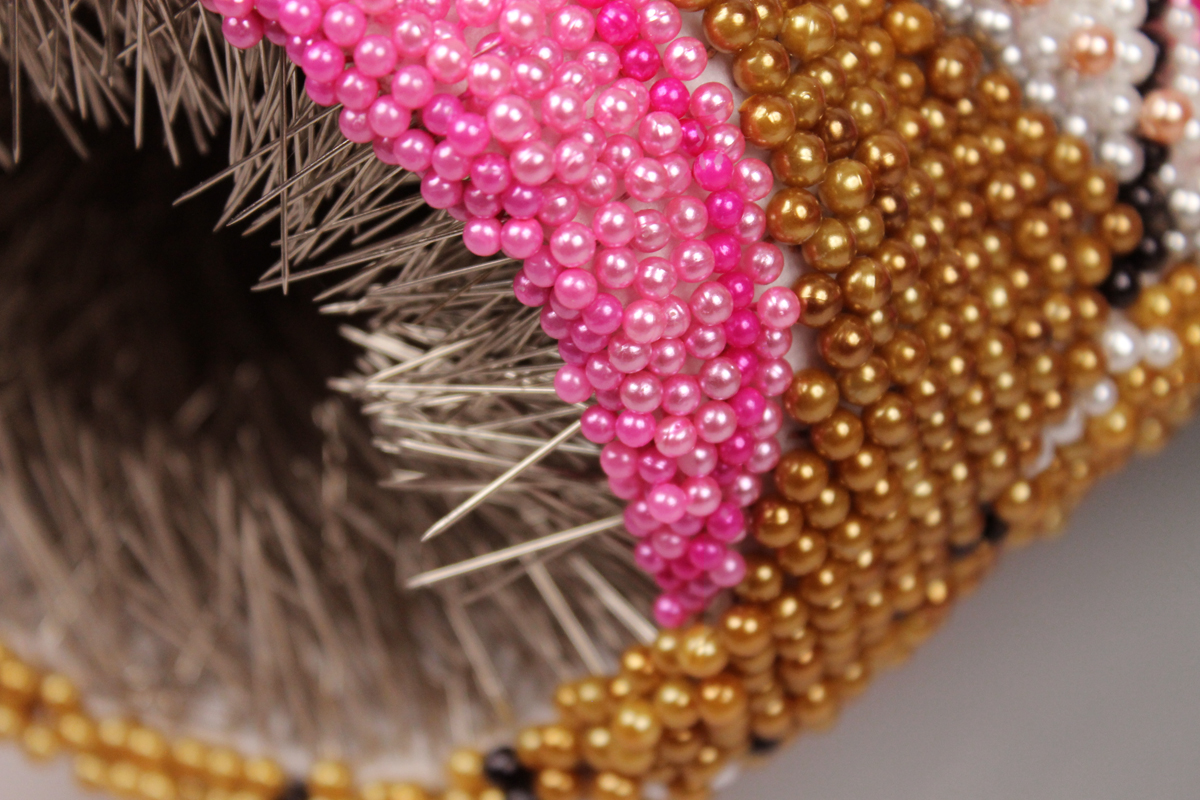 Detailed photo of work by Angela Ellsworth showing pink and gold beads.