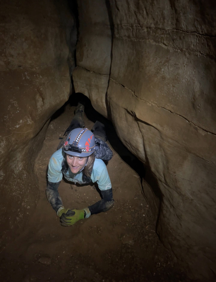 Artist Erika Jaeggli peers out from deep inside a cave.