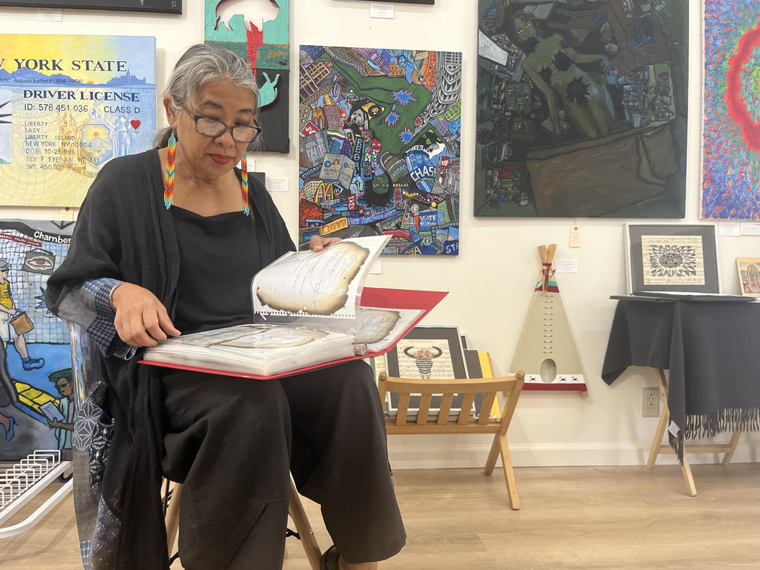 Burmese artist, activist, and asylee Chaw Ei Thein examines notebook pages by friend and fellow artist Sitt Nyein Aye.