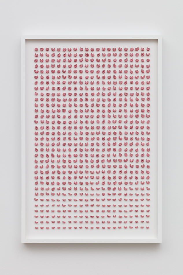 Photo of artwork by Denver-based artist Joel Swanson, which shows the horseshoe-shaped marshmallows from Lucky Charms cereal arranged on a wood panel.