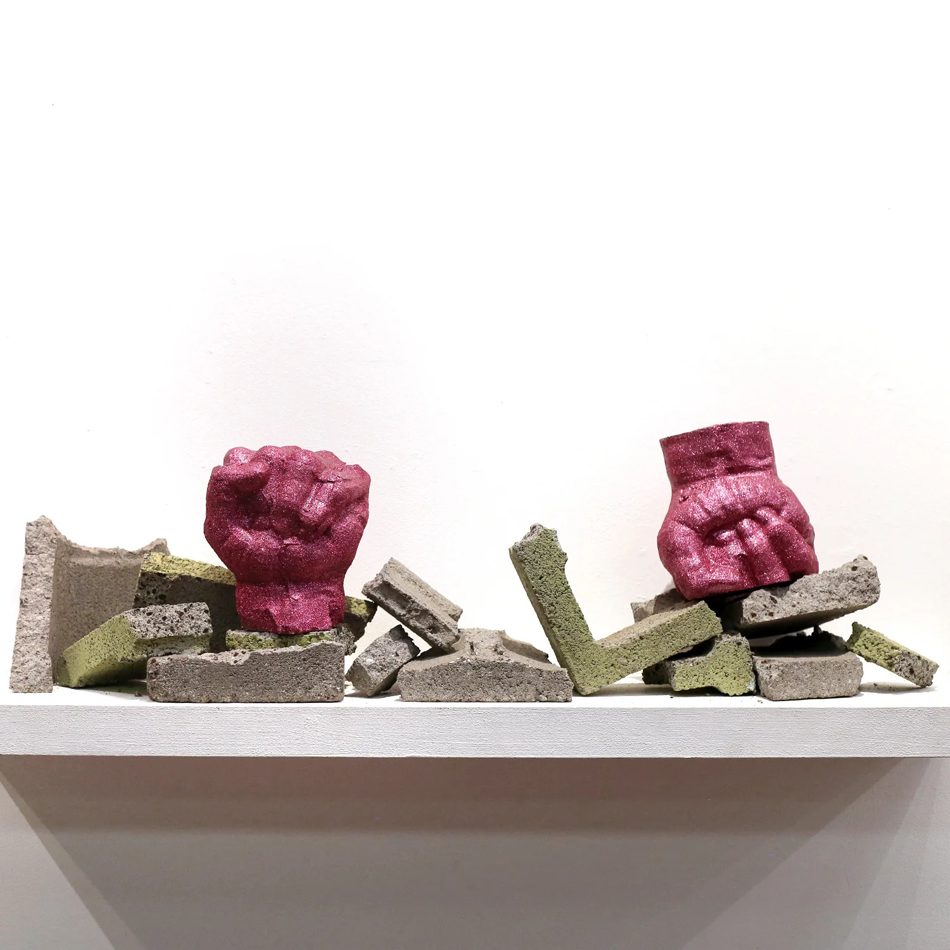 Two adjacent sculptures of glittery pink fists atop broken cement blocks. By Phoenix-based artist Philip Gabriel Steverson.