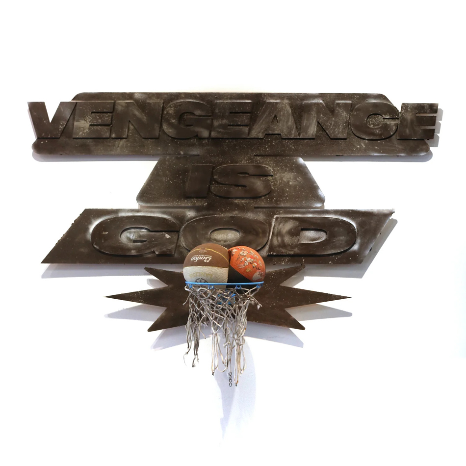 Mixed media sculpture of a basketball hoop with the words "Vengeance is God" and two conjoined basketballs in the rim. By Phoenix-based artist Philip Gabriel Steverson.