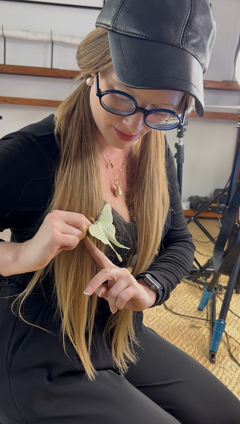 Portrait of artist Virginia L. Montgomery handling a lunah moth.
