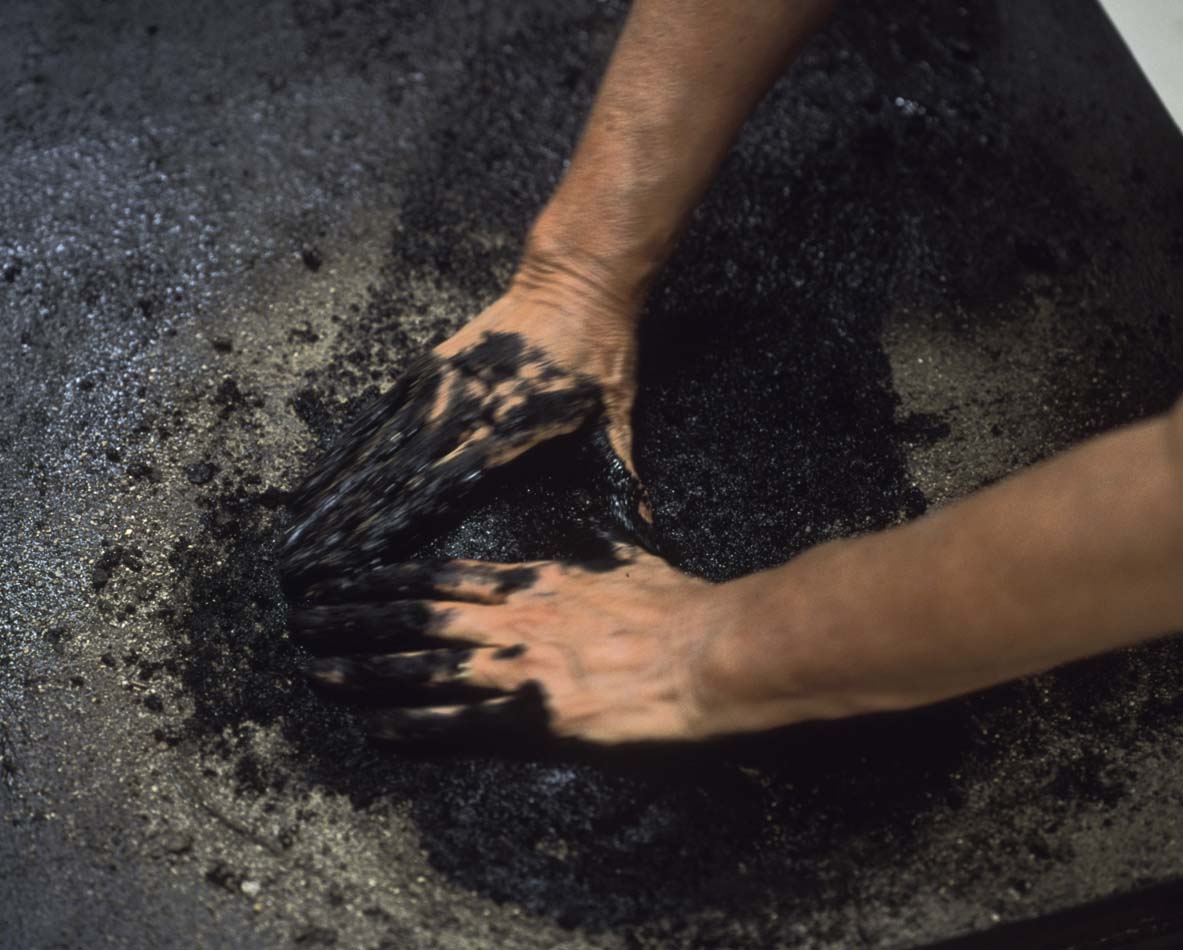 Judy Tuwaletstiwa working in her studio mixing black pigment.