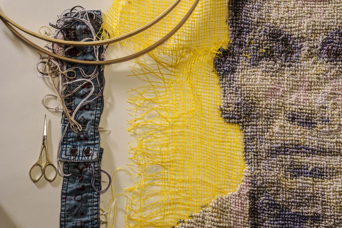 Detail view of a portrait of cross-stitch on produce bags. 