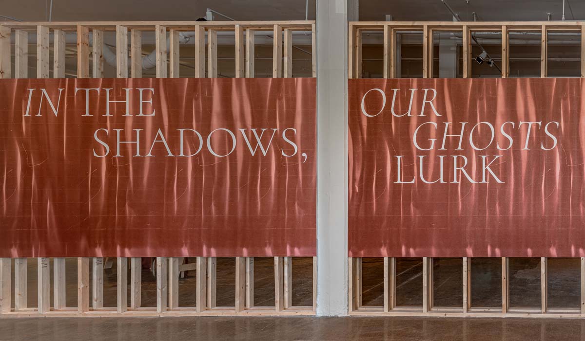 In the Shadows Our Ghosts Lurk (En Las Sombras, Nuestros Fantasmas Acechan), installation view of title wall with graphic of artwork by Daniel Monroy Cuevas, Contemporary at Blue Star, 2025. 