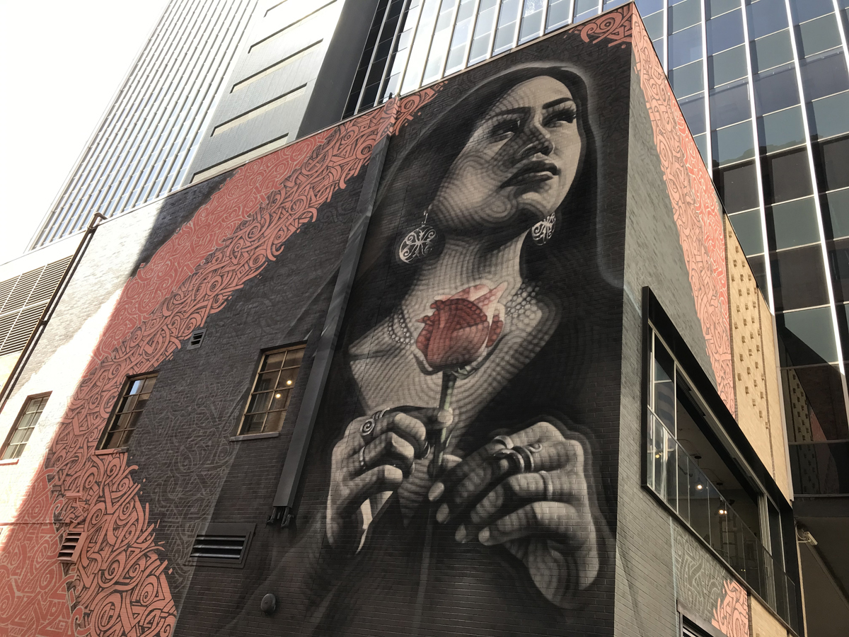 Phoenix mural depicting a woman with uplifted gaze, holding a flower, part of the essential Southwest Mural Guide.