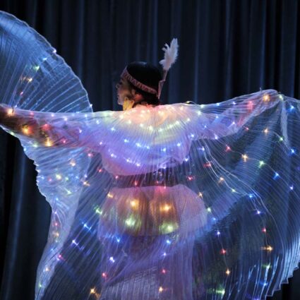 IAIA student wearing clothing with colorful lights while performing at the annual benefit and auction.