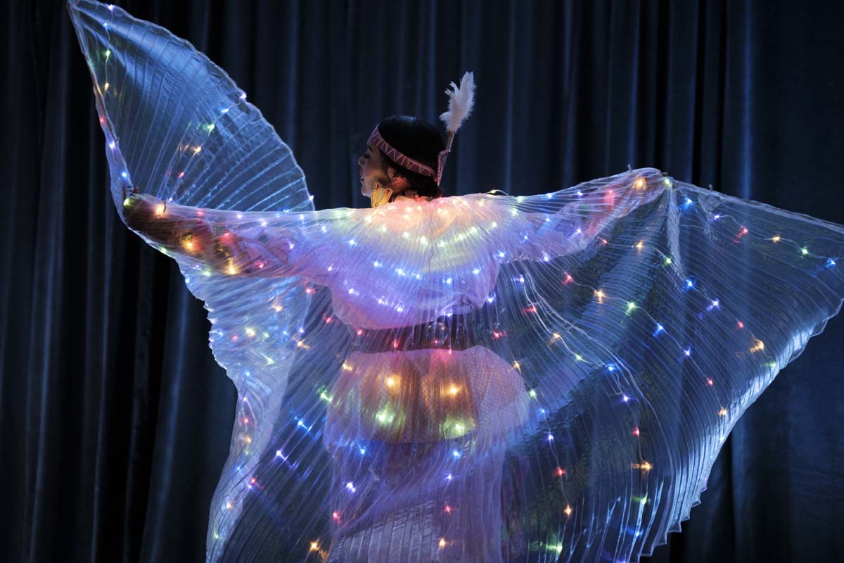 IAIA student wearing clothing with colorful lights while performing at the annual benefit and auction.