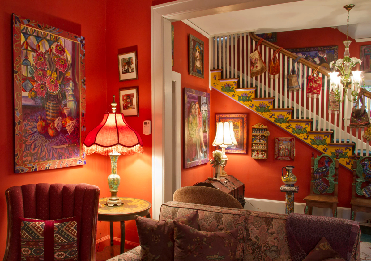 Lamps illuminate clusters of paintings on the warm red walls of the Pilar Pobil estate in Salt Lake City.