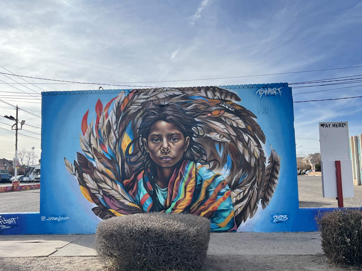 Albuquerque mural of an Indigenous child encircled by feathers by Bimmer Torres.