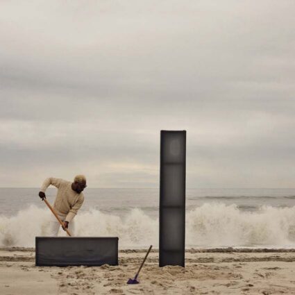 James Perkins at work on Fire Island with two post totems on the sand.