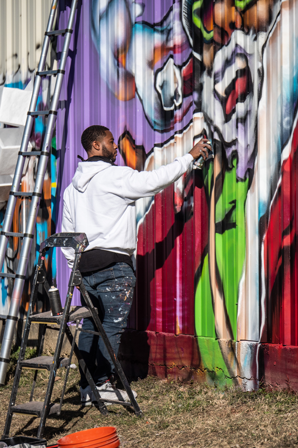 Artist Trey Wilder works on his Dallas mural Two Turtle Doves.