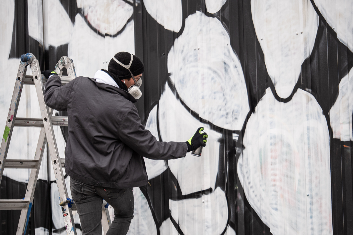 Will Heron wields a spray paint can as he paints his Dallas mural Six Geese a Laying.