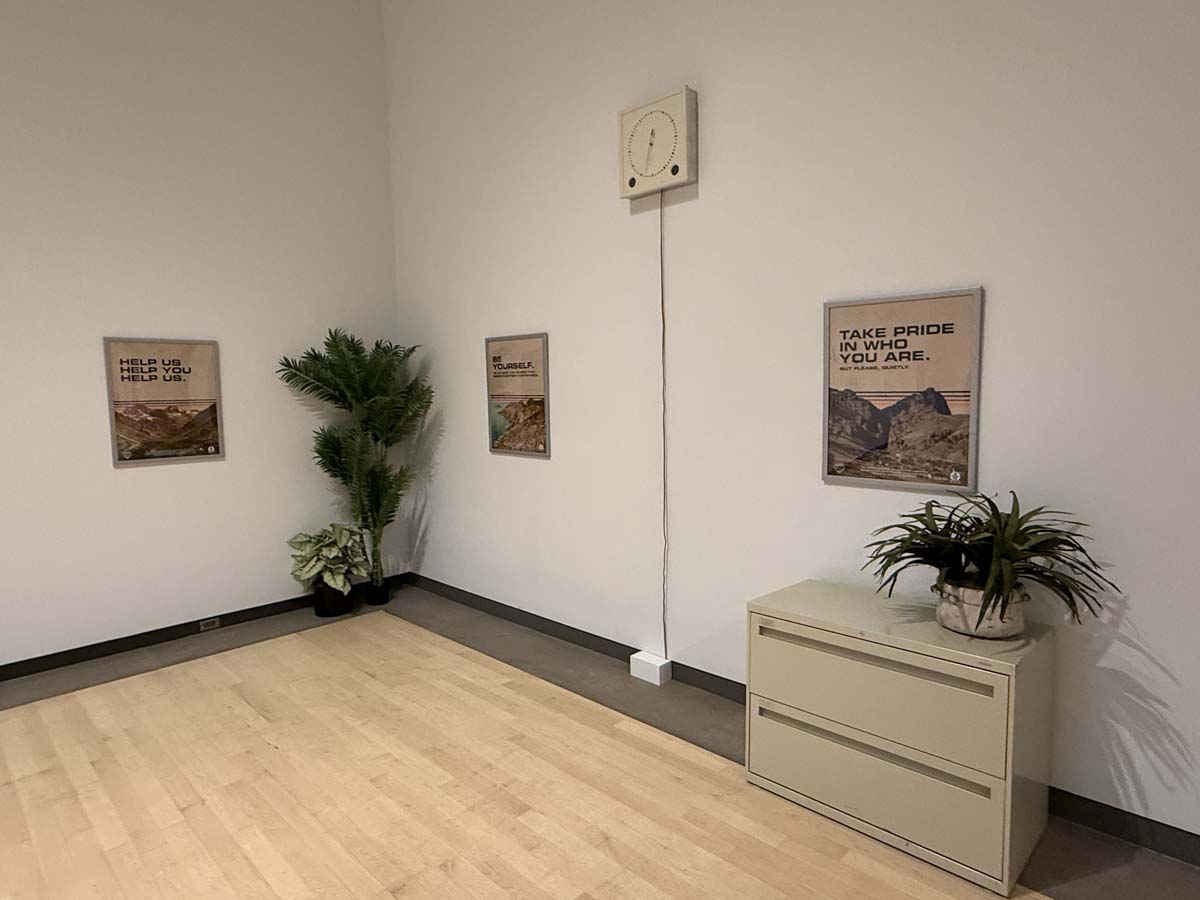 Installation view of T.U.L.I. with motivational posters and office plants.