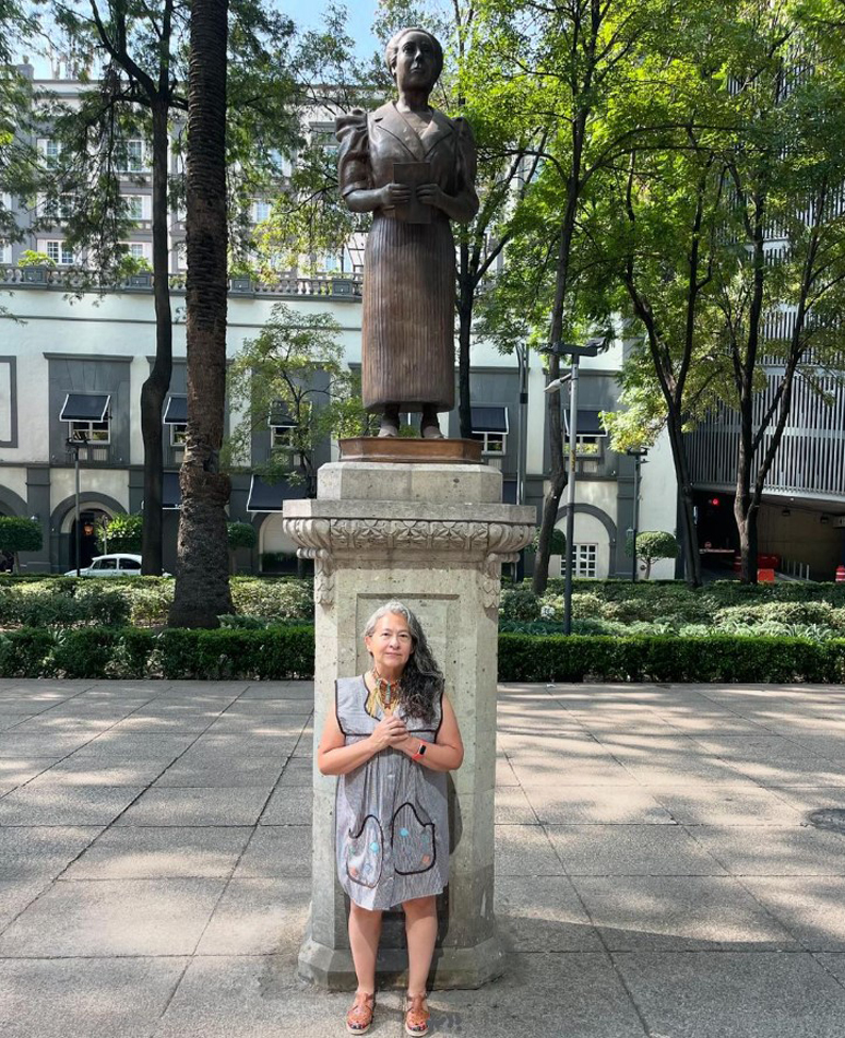 An artist stands in front of a statue in CDMX. The Apapacho residency is just one of the top Mexico City artist residencies on this comprehensive list for visual artists and curators.