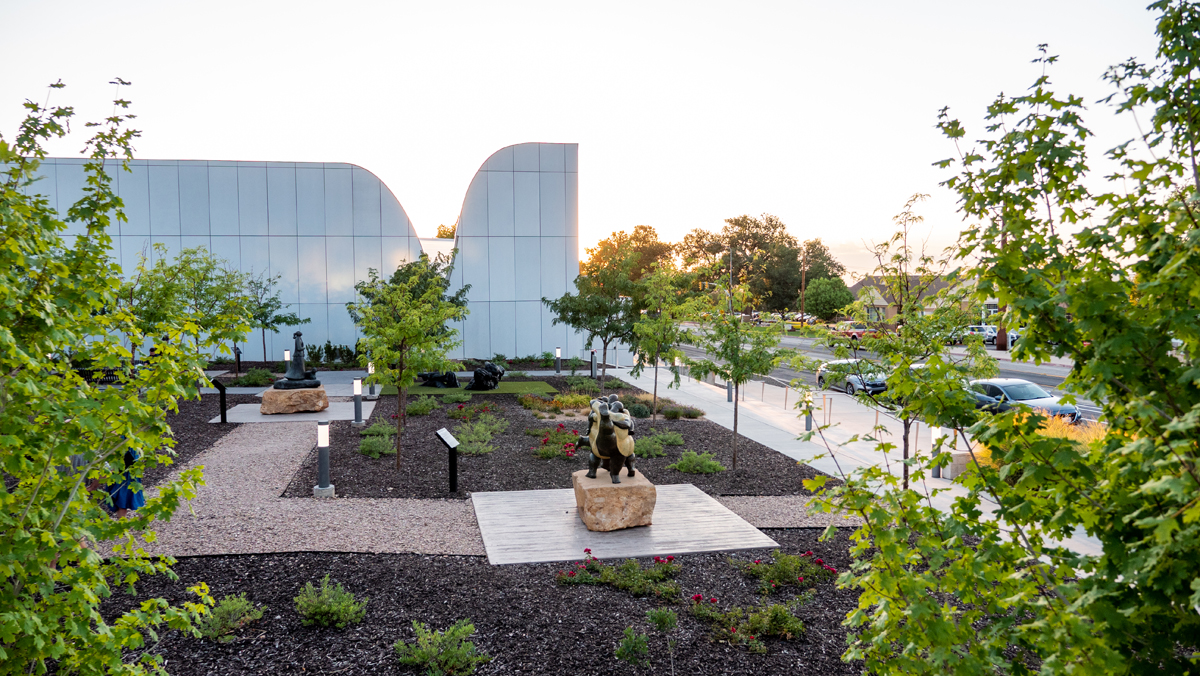 A sculpture park outside a sleek, curvilinear art museum.