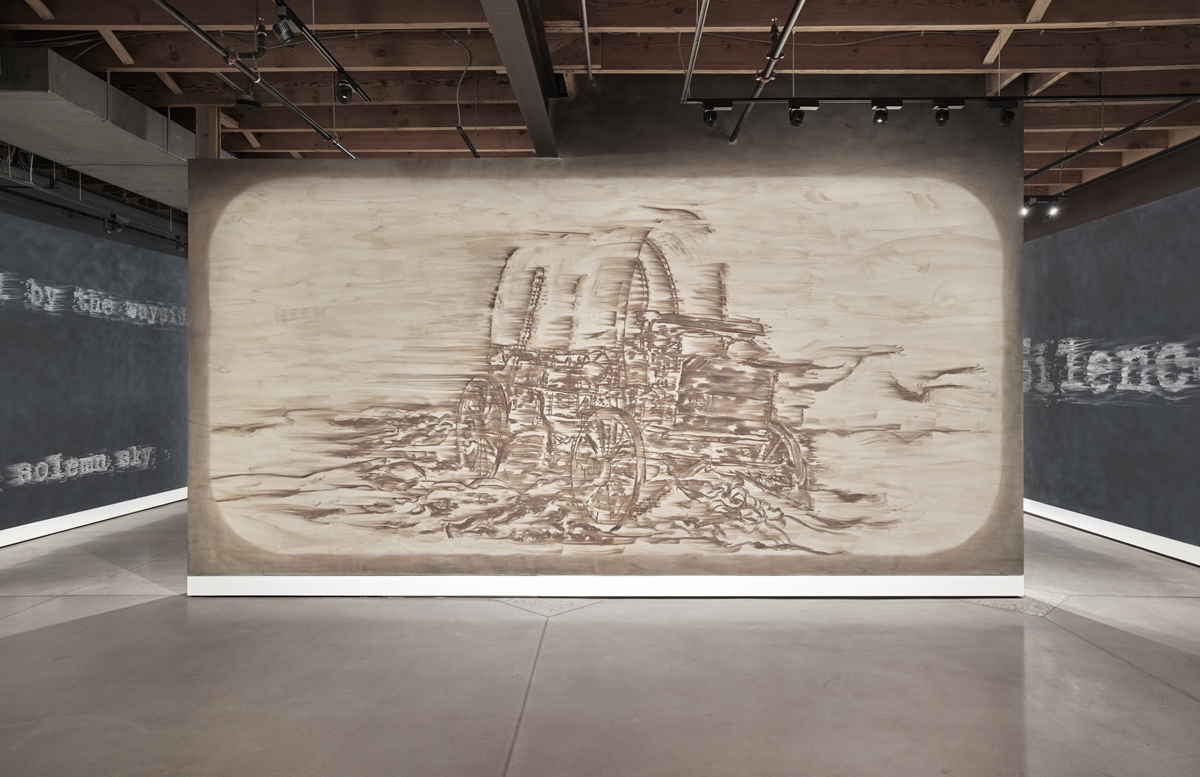 Installation view of Gary Simmons: Rush at Cookie Factory in Denver, showing a wall drawing of a covered wagon.