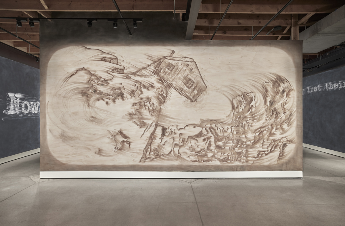 Installation view of Gary Simmons: Rush at Cookie Factory in Denver, showing a wall drawing of Charlie Chaplin's cabin teetering on the edge of a cliff.