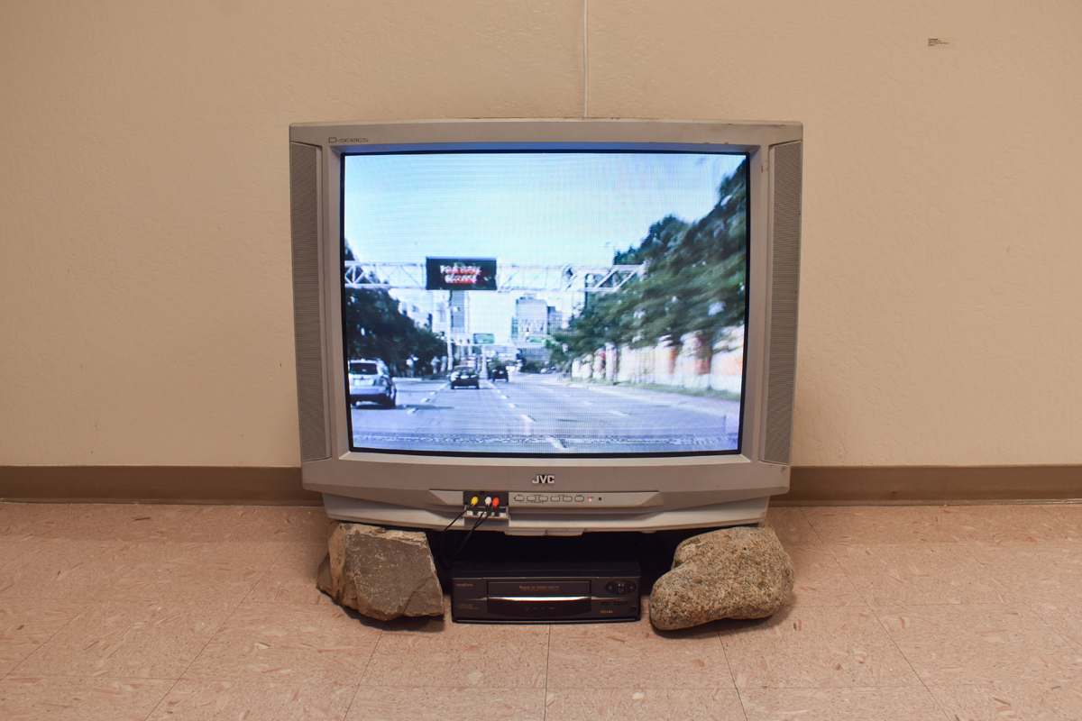 Installation view of a multimedia installation incorporating a television and rocks by Luke Rizzotto.