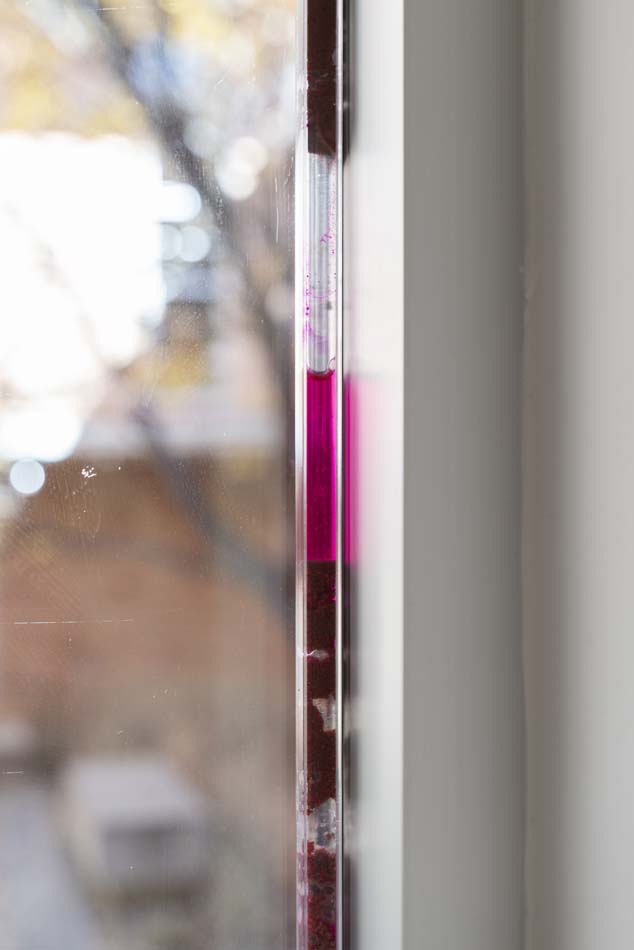 tract (aquifer) (2026), plastic polycarbonate tubes filled with the liquid dye and clusters of dye-soaked sediment sit pressure-fitted into the upper window frames of the gallery. 