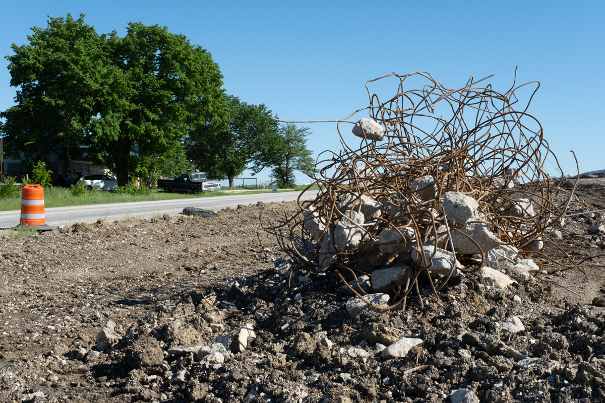 Photograph of a tangle of wire and stones on a roadside.