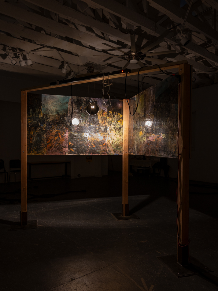 Inkjet prints, asphalt reclaimed from roadsides and parking lots, salvaged plexiglass,headlight shells, bass shaker surface transducers, speaker wire, fir, steel, electricity