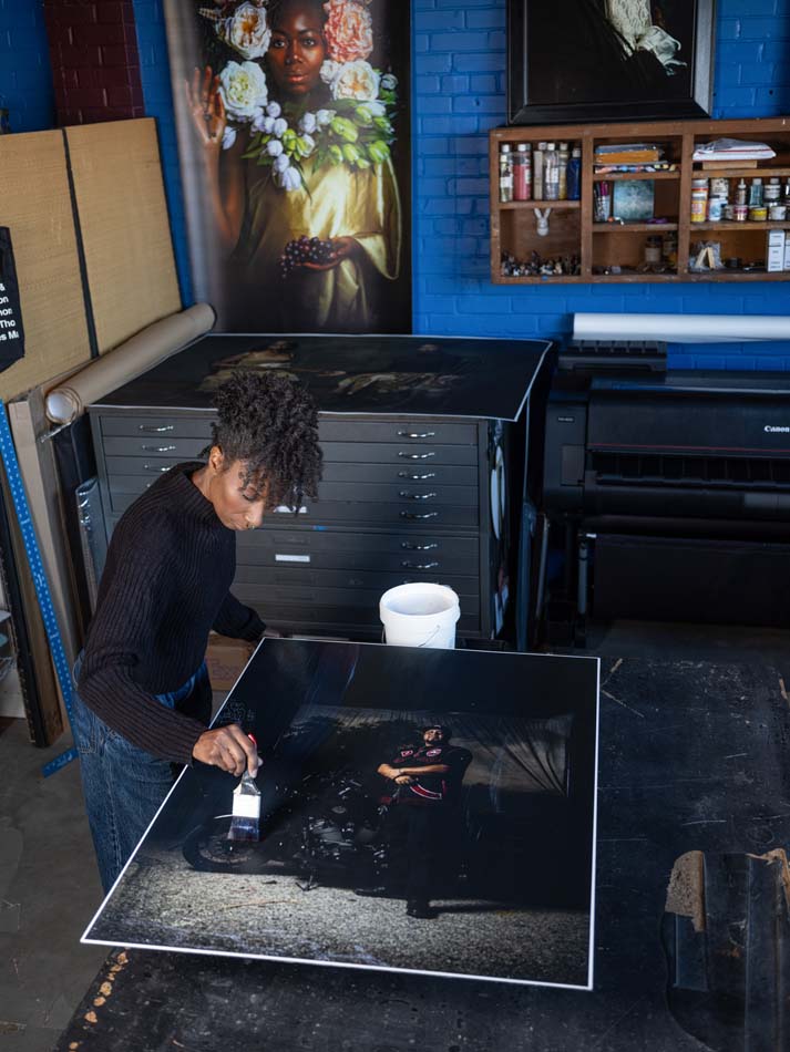 Alanna Airitam hand- varnishes a photograph in her studio.