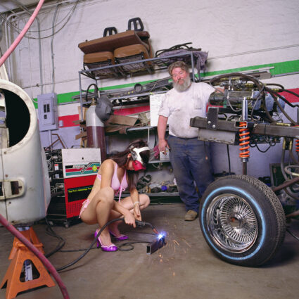 Self-portrait of Liz Cohen welding in an auto shop.