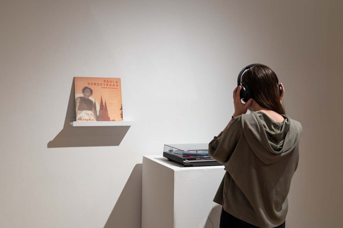 A viewer listening to a work by Kalup Linzy through headphones