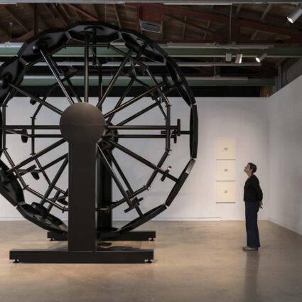 Installation view showing A Clockwork, a Ferris wheel of black prison tables welded together