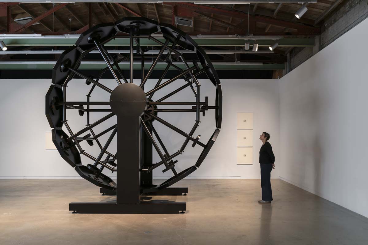 Installation view showing A Clockwork, a Ferris wheel of black prison tables welded together