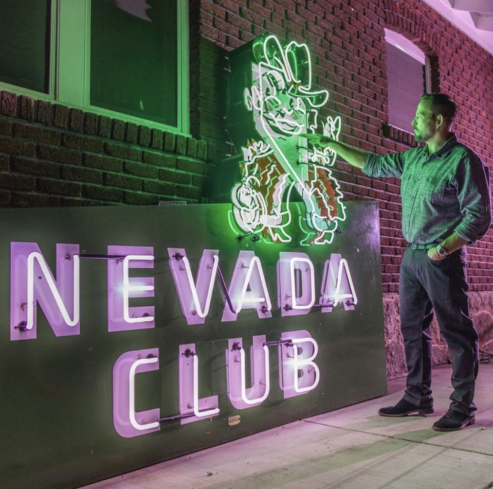 Portrait of neon collector Will Durham in front of a salvaged neon sign.