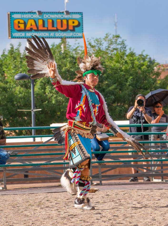 Eagle dancer from the Zuni Niiha Dance Group at the Gallup Summer Indian Dances, with Gallup sign in the background.