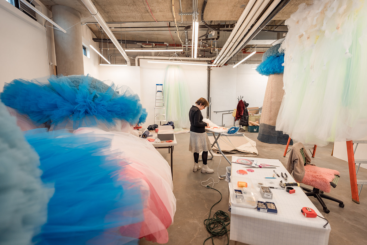 Process shot of Colorado-based, Argentinian artist Ana María Hernando with a mountain of tulle behind her.