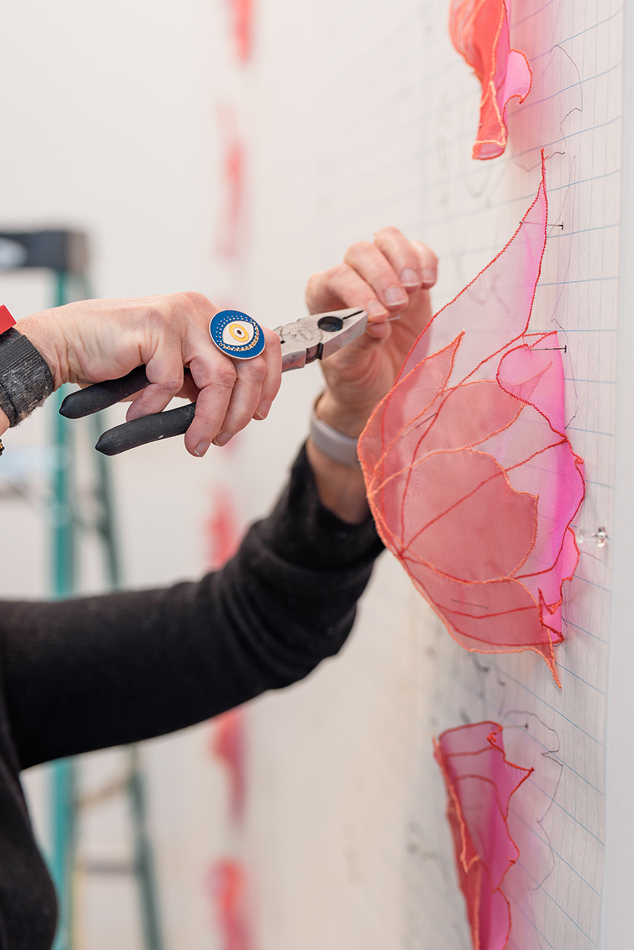 Detail of an artist manipulating tulle in her studio.