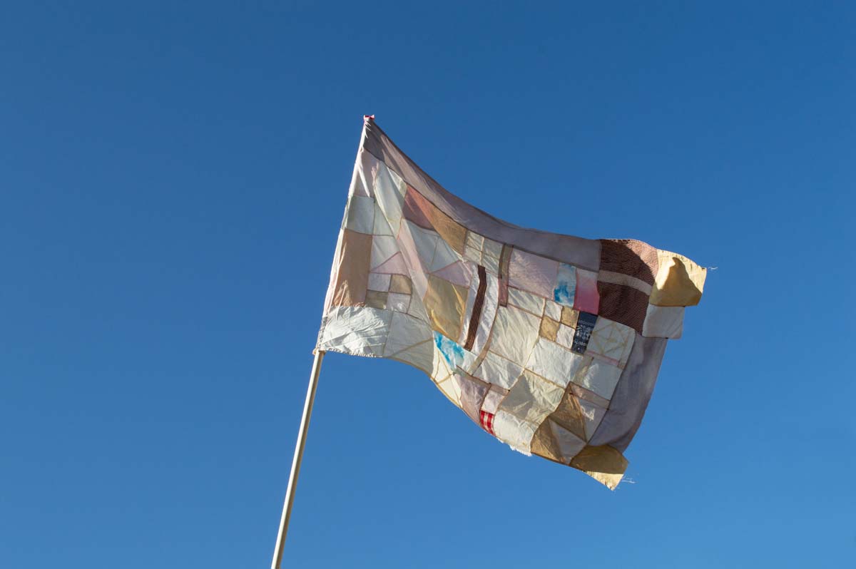 A flag made of Found fabrics; natural dyes made with cochineal, onion skins, rosemary, creosote, pecan shells