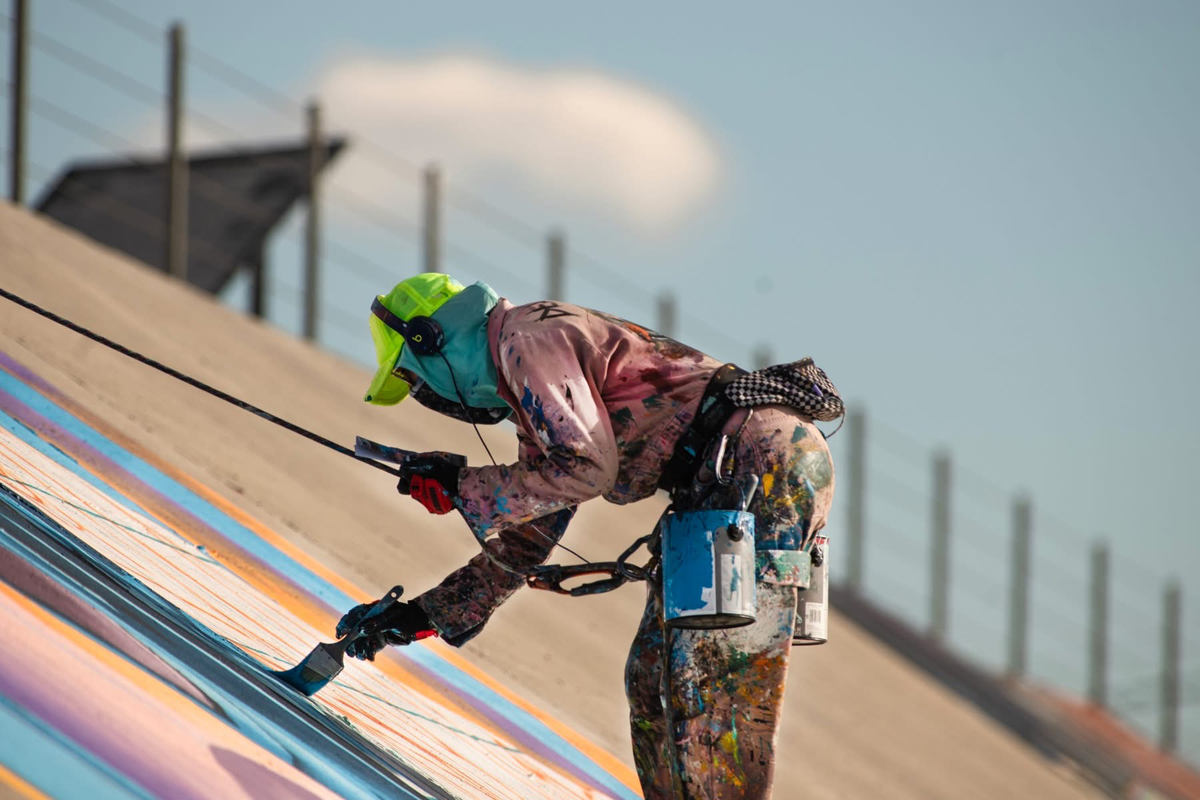 An artist rappels to add to the Pueblo Levee Mural Project.